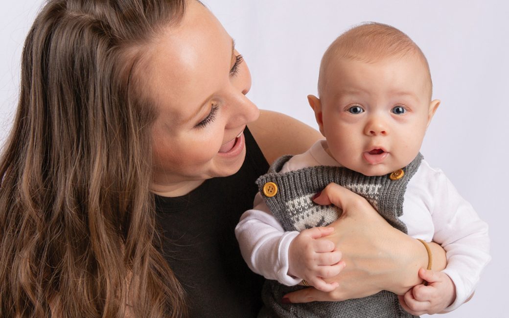 Mom Angela smiling and holding and looking at baby Eli