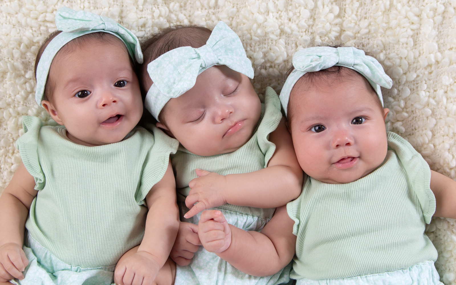 Baby triplets wearing headbands with bows